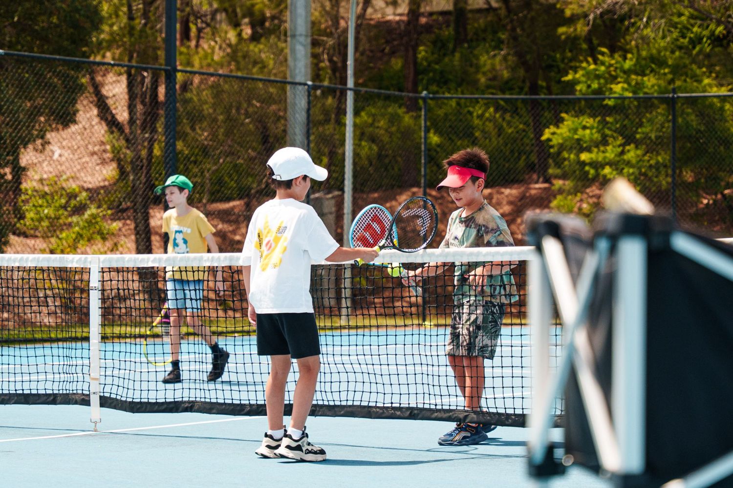Two juniors touching racquets at the net