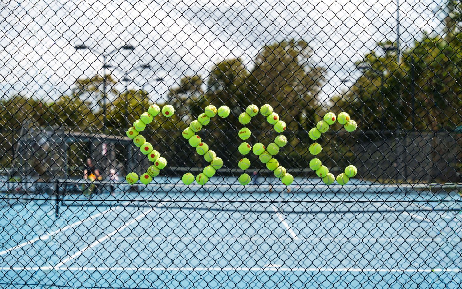 SRC spelled out in tennis balls on the court fence